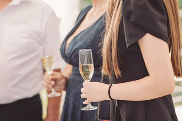Celebration with sparkling drinks, elegant attire, and joyful people enjoying special moments outdoors during a sunny afternoon gathering