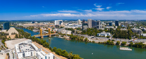 Aerial image of Sacramento, California, featuring the Tower Bridge, State Capitol Building, Ziggurat Building, and Sacramento River under a clear sky.