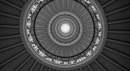 Architectural detail of a spiral staircase shot from the bottom looking up, emphasizing the elegant geometric pattern. Monochrome conversion.
