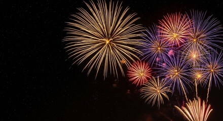 Fototapeta premium Night sky filled with colorful fireworks exploding in bright golden, red, and purple tones. The fireworks light up against a dark, starry sky, creating a festive and celebratory atmosphere