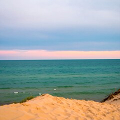 Golden sand dunes overlook a calm blue sea and sky