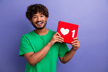 Young Man Holding a Social Media Like Icon Against a Purple Wall Promoting Connection and Online Engagement