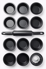 Black baking pans and rolling pin flat lay on white background