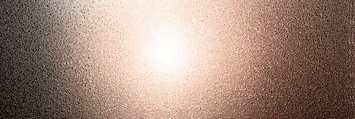 Abstract close-up texture of a rough, metallic surface with a light copper or rose gold patina finish, featuring a bright light reflection at the center.
