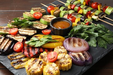 Vegetarian barbecue. Tasty grilled vegetables, parsley and sauce on wooden table, closeup