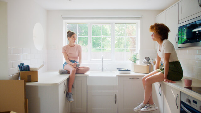 Two Female Friends Or Same Sex Couple Taking A Coffee Break From Unpacking On Moving Day In New Home