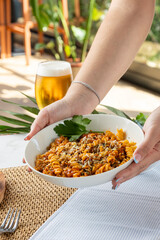Hands serving fusilli pasta with bolognese sauce and beer