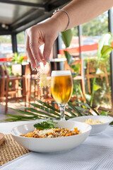 Hand sprinkling cheese on pasta with beer