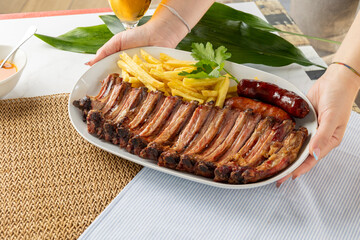 Serving grilled pork ribs, french fries, and sausage platter