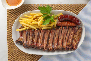 Grilled pork ribs platter with french fries and sausages