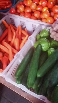 Fresh vegetables arrangement, carrots, cucumbers, tomatoes, chayote on market display.