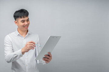A handsome young Asian man looks pleasantly surprised while reviewing a document or financial statement. This concept is ideal for business, finance, investment, technology, and advertisement.

