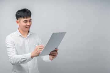 A handsome young Asian man looks pleasantly surprised while reviewing a document or financial statement. This concept is ideal for business, finance, investment, technology, and advertisement.

