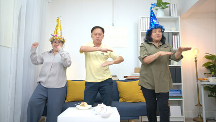 Happy elderly man blowing out birthday candles surrounded by friends