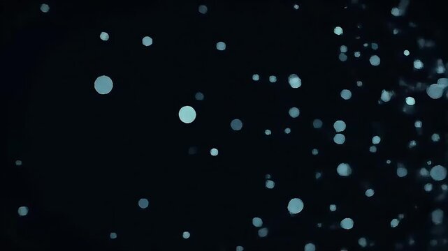 Shimmering light particles floating on a dark background, creating an abstract and serene bokeh