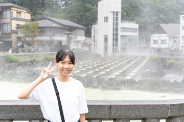 草津温泉旅行で湯畑に来ている10代の女性