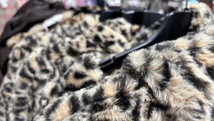 Eco-friendly faux fur coats for autumn and winter on hangers in clothing store. Warm sustainable...