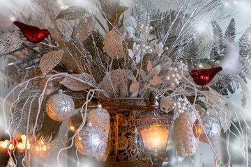 Blurred frosty Christmas background with winter bouquet, red birds on white branches and soft light bokeh, selective focus
