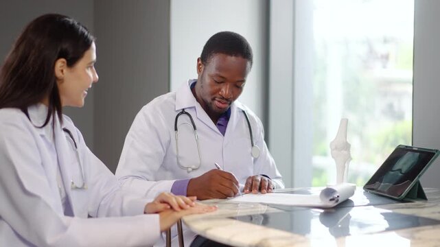 Two doctors engage in an important discussion about patient care at a clinic. They review documents and use a tablet computer for important health information and prescriptions, advice at hospital