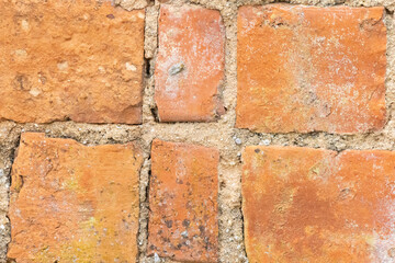 Close up of orange brick wall showing deterioration and mortar joints