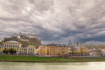 Salzburg old town skyline with river fortress and dramatic cloudy sky

