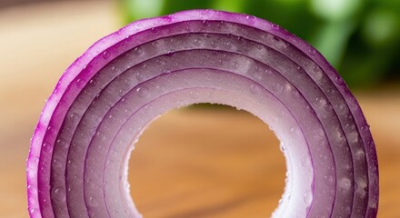 A macro photograph presents a detailed view of a red onion slice, showcasing concentric layers and water droplets, with the central opening perfectly framed.