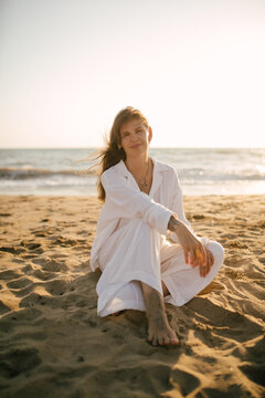 Beautiful 40 years old woman relaxing on the beach at sunset.