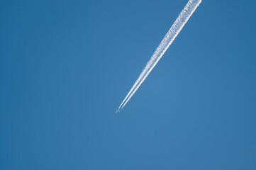 A350 airliner with contrail against a blue sky.