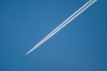 A350 airliner with contrail against a blue sky.