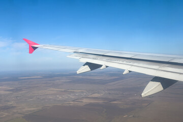 View from the airplane window at a beautiful cloudy sky and the airplane wing. Earth and sky as seen through window of an airplane. Travel concept. Copy space
