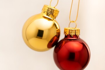 Closeup of red and gold christmas baubles hanging, creating a festive and celebratory atmosphere on white background