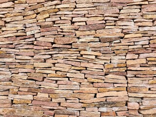 Textured sandstone wall. Stacked stones of various shapes and sizes create a strong decorative background in natural warm tones.