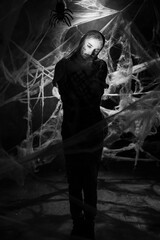 art portrait of a young man with ugly makeup wrapped with cobwebs.