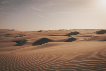 Wind-sculpted sand dunes at sunset in the desert near Huacachina, Peru.