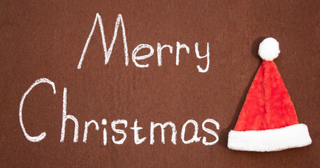 Merry Christmas handwritten in chalk next to Santa's hat