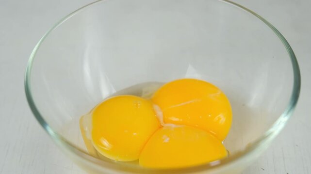 Putting egg yolk to glass bowl cooking food on kitchen at home. Recipe cuisine culinary ingredient. Baking, preparing eggs dish. Healthy organic protein in chicken eggs.