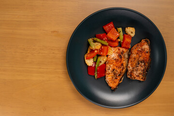 Grilled or Fried salmon steaks with fresh vegetables on plate. Top view on wooden table.