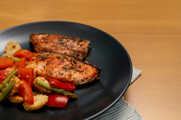 Grilled or Fried salmon steaks with fresh vegetables on plate on wooden table.
