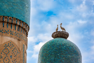 Figures of storks in a nest on top of turquoise dome of Chor Minor madrasah against sky in Bukhara, Uzbekistan. Chor Minor or Madrasah of Khalid Niaz-gul. Built in 1807