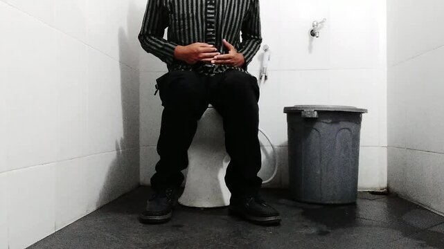 A man is poop sitting on a toilet, struggling with stomach and gastric pain, representing an unhealthy lifestyle