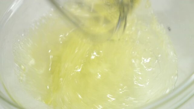 Cooking mixing sugar with egg white in glass bowl using metal whisk on kitchen at home. Recipe cuisine culinary ingredient. Baking, preparing food dish. Healthy protein in chicken eggs.
