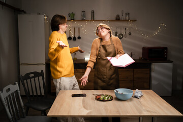 Young couple prepare vegetable salad read cookbook discuss recipe in kitchen at home. lifestyle concept.