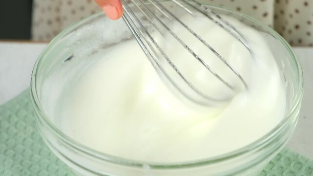 Woman hands cooking mixing sugar with egg white to foam in bowl using metal whisk on kitchen at home. Recipe cuisine culinary ingredient. Baking, preparing food dish. Healthy protein in chicken eggs.