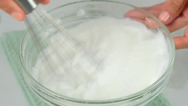 Woman hands cooking mixing sugar with egg white to foam in bowl using metal whisk on kitchen at home. Recipe cuisine culinary ingredient. Baking, preparing food dish. Healthy protein in chicken eggs.