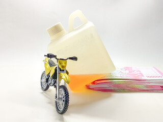 A conceptual image illustrating the expensive cost of gasoline, featuring a toy motorcycle, spilled fuel, and a stack of money
