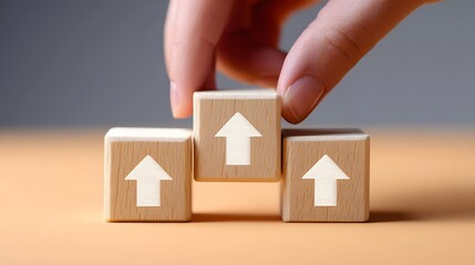 A hand arranging wooden blocks with upward-facing arrows, representing the concept of growth, progress, and moving forward towards goals and aspi ns.