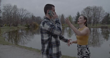 A young couple shares a heartwarming moment by a tranquil lake in a beautiful park. After a brief disagreement over a phone call, they reconcile, laugh, and connect, symbolizing love and togetherness. - Powered by Adobe