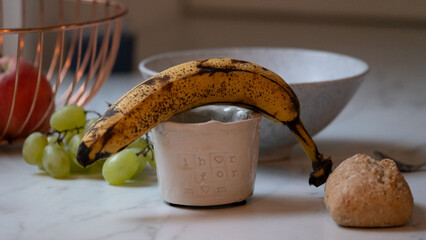 Ripe banana with bread and fruit on kitchen table