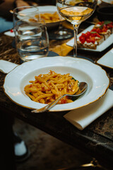 A beautifully plated trofie pasta dish, served with a rich sauce on an elegant table in an upscale Italian restaurant. Appetizers and drinks complete the luxurious dining experience.