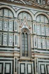 Close-up of the stunning green and white marble facade of Florence Cathedral, showcasing intricate patterns, detailed windows, and classic Renaissance architectural elements.